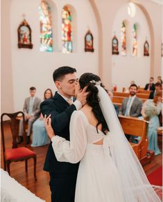 a bride and groom kissing in the church