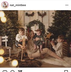 three children are sitting in front of christmas trees