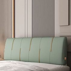 a bed with a green headboard next to a white wall and wooden paneling