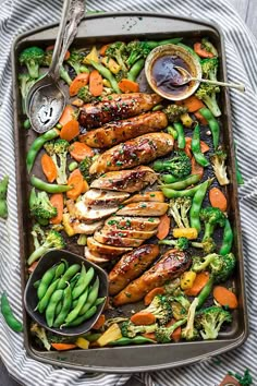 a sheet pan with chicken, broccoli, carrots and green beans on it