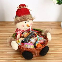 a stuffed snowman sitting in a basket filled with candy and candies on top of a wooden table