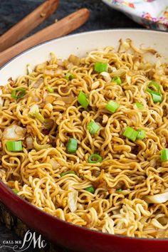 a red bowl filled with noodles and green onions