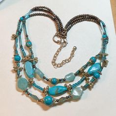 A bright and fresh vintage beaded necklace in blue and turquoise hues. The necklace is about 20 to 23 inches long.  Silvertone metal, with darker silvercolored beads.  Bright faux turquoise and blue plastic beads.  Also bugle beads and little Charlotte beads.  Lobster claw clasp.  Chain extender.  No stamps or marks.  Good vintage condition, with some surface wear, and some wear and discoloration to the metal. You can find more vintage necklaces here: https://www.etsy.com/shop/OtterCatHaus?section_id=17074037&ref=shopsection_leftnav_1&view_type=list Please convo with any questions.  I combine shipping, and refund overages of more than fifty cents.  Thanks for stopping by today. Multi-strand Metal Beads Jewelry, Blue Multi-strand Beaded Necklace With Dangling Beads, Blue Double Strand Beaded Necklace With Polished Beads, Blue Double Strand Bohemian Turquoise Necklace, Bohemian Double Strand Turquoise Necklace, Bohemian Blue Double Strand Turquoise Necklace, Adjustable Multi-strand Turquoise Beaded Necklace, Blue Double Strand Gemstone Beaded Necklaces, Blue Bohemian Double Strand Necklaces