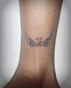 an angel wing tattoo on the back of a woman's leg, which reads r