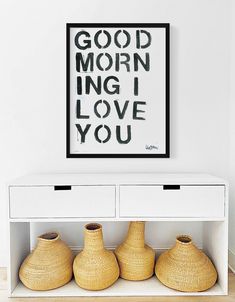 three vases sitting on top of a white shelf in front of a framed poster