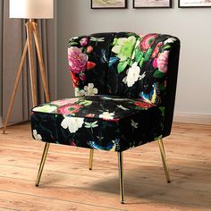 a black floral chair with gold legs on a wooden floor