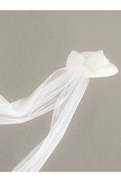 a white veil with a flower on it is hanging from the ceiling in front of a wall