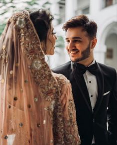 a man in a tuxedo standing next to a woman