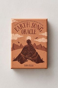 the book earth - song oracle is sitting on top of a white surface with mountains in the background