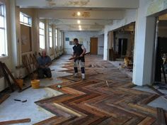 two men are standing in the middle of a large room with wood flooring on it