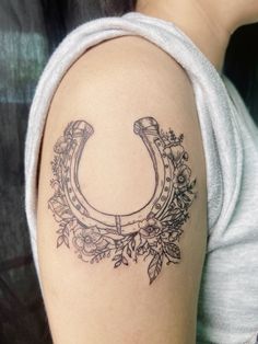 a woman with a tattoo on her arm that has a horseshoe and flowers around it