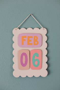 a sign hanging on the wall that says feb 006 in pink and orange