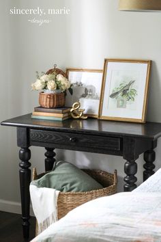 a black table with two pictures on it and a basket full of flowers next to it