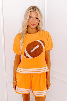 - Be ready for touchdowns and tailgates with this sparkling top! Its super cute sequined football design and jersey-style accent stripes are perfect for bringing a bit of glam to game day. Put a trendy twist on sporty style with this adorable piece! Show your team spirit with our vibrant clothing collection inspired by the bold colors of popular college football teams like the University of Tennessee Volunteers and the University of Texas Longhorns. - Unlined cotton-blend material - A crew cut n Sporty Short Sleeve Tops For Tailgating, Team Spirit Tops For Tailgating During Football Season, Team Spirit Tops For Tailgating During Sports Season, Team Spirit Tops For Sports Season Tailgating, School Spirit Tops For Tailgating During Football Season, Sporty Tops For Football Season Fan Gear, Sporty Football Season Fan Gear Tops, Collegiate Tops For Game Day During Football Season, School Spirit Tops For Football Season Sports Events