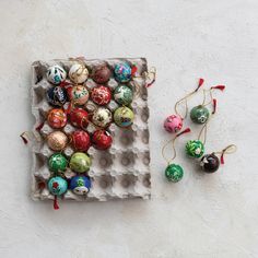 an egg carton filled with assorted ornaments next to a ceramic ornament