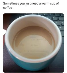 a coffee cup sitting on top of a laptop computer next to a keyboard with the caption, sometimes you just need a warm cup of coffee