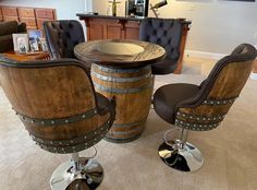 two chairs and a table made out of wine barrels in a room with carpeted flooring