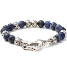 This piece is a unique blend of two exceptional materials. One is Sterling Silver that the master craftsman John Varvatos often uses to elevate the design of metal features and add a layer of luxury to the piece. The other is Sodalite. He uses this rare gemstone only when the item demands natural aquatic tones no other stone can match. Sodalite can be found only in a few places around the world. Only a small percentage of those qualify as jewel-worthy. And an even smaller percentage of those are Elegant Lapis Lazuli Gemstone Bracelets, Luxury Hand-strung Silver Jewelry, Elegant Handmade Lapis Lazuli Bracelets, Luxury Sterling Silver Beaded Bracelets, Artisan Blue Sterling Silver Bracelets, Artisan Blue Sterling Silver Bracelet, Luxury Blue Round Bead Bracelets, Luxury Sterling Silver Round Bead Bracelets, Adjustable Elegant Lapis Lazuli Bracelets