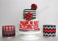 a three tiered cake decorated with red flowers and black and white stripes, sits on a pedestal