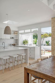 an open kitchen with white cabinets and wooden table in front of the countertop area