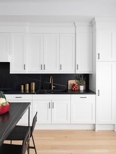 a kitchen with white cabinets and black counter tops