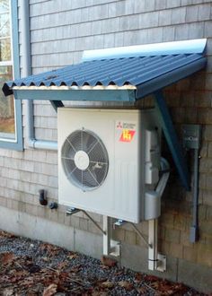 an air conditioner sitting on the side of a house next to a wall with a metal roof