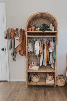 an open closet with clothes hanging on the wall and baskets in front of it, next to a door