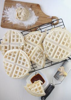 four waffles on a cooling rack with some butter and syrup next to them