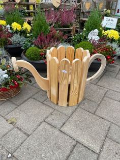 a teapot shaped planter made out of wooden slats sits on the ground surrounded by potted plants