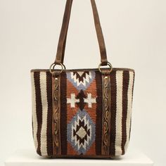 This Ariat wool blanket tote by M&F Western Products is brown with orange, blue and ivory in a southwestern pattern. Genuine leather on back, on handles and edge tooling. Zip closure on top of back to keep your items safe. Details Ariat Wool Blanket Tote Brown Measures: 15 x 13 x 4-1/2 Southwestern Pattern Genuine Leather Inside 2 Small Pockets, 1 Large Zip Pocket Zip Closure Brown Southwestern Style Shoulder Bag For Everyday Use, Southwestern Brown Rectangular Shoulder Bag, Southwestern Style Brown Rectangular Shoulder Bag, Brown Southwestern Rectangular Shoulder Bag, Southwestern Patterns, Brown Tote, Cooling Blanket, M F, Stay Cozy