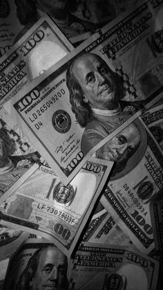 many hundred dollar bills spread out on top of each other in black and white photo