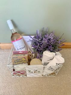 a white basket filled with lots of different items next to a wine bottle and flowers