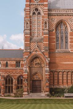 an old brick building with a clock on it's side and grass in front