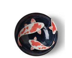 a black bowl with red and white fish painted on it