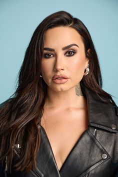 a woman with long hair wearing a black leather jacket and piercings on her neck