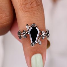 a woman's hand with a ring on it and a black stone in the middle