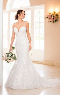 a woman in a white wedding dress holding a bouquet and smiling at the camera while standing in front of a doorway