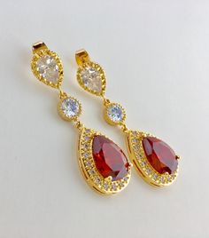 I've created these gorgeous red ruby cubic zirconia bridal tear drop earrings in gold plated brass setting. Earrings feature a large teardrop with pear cut red ruby cubic zirconia center surrounded by tiny round zirconia crystals. Teardrop dangles from a clear cubic zirconia ear stud and a round cubic zirconia connector. Total length of the earring is 4.8 cms. For matching necklace click: https://www.etsy.com/listing/667778454/red-bridal-gold-necklace-red-crystal?ref=related-6 For matching brace Red Ruby Pear-shaped Earrings, Elegant Red Teardrop Bridal Earrings, Glamorous Red Earrings For Wedding, Elegant Red Bridal Earrings For Anniversary, Glamorous Red Wedding Earrings, Red Pear-shaped Wedding Earrings, Red Ruby Earrings For Wedding, Red Ruby Wedding Earrings, Red Gold Plated Earrings For Party