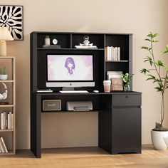 a computer desk with a monitor and keyboard on it in front of a bookshelf