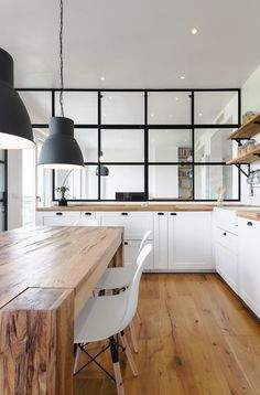 an open kitchen with white cabinets and wooden counter tops, along with black pendant lights hanging from the ceiling