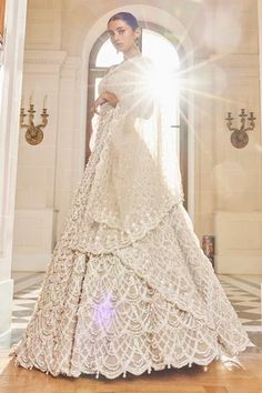 a woman in a wedding dress standing on a wooden floor with sunlight shining through the window