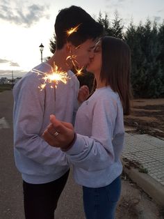 two people kissing while holding sparklers in their hands