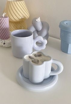 coffee cups and saucers sitting on a white counter top next to a lamp shade