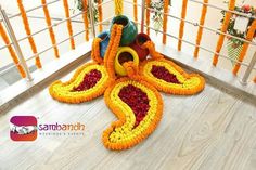 an arrangement of flowers on the ground in front of a railing with orange and yellow decorations