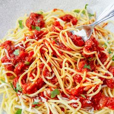 a plate full of spaghetti with sauce and parsley on the side, ready to be eaten