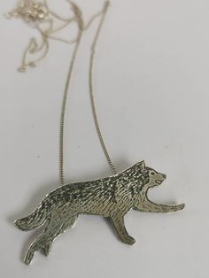 a silver necklace with a wolf on it