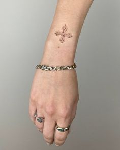 a woman's wrist with a cross tattoo on it