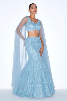 Blue mermaid style lehenga embellished with sequin scallop patterns. Comes with padded blouse with cape sleeves. 
Components: 2
Pattern: Embroidered
Type Of Work: Sequin
Neckline: V-neck
Sleeve Type: Cape sleeves
Fabric: Organza, net, Lining: Satin
Color: Blue
Other Details: 
Attached lining
Model Height: 6ft wearing size XS
Length: Lehenga: 45 inches
Closure: Lehenga and Blouse: Side zip
Occasion: Sangeet,Cocktail - Aza Fashions Fitted Gown With Cape Sleeves For Festive Occasions, Festive Fitted Gown With Cape Sleeves, Fitted Gown With Dupatta And Cape Sleeves, Blue Lehenga With Cape Sleeves And Dupatta, Blue Lehenga With Cape Sleeves For Wedding, Fitted Sharara With Sheer Dupatta And Cape Sleeves, Fitted Gown With Sheer Dupatta And Cape Sleeves, Fitted Lehenga With Cape Sleeves For Evening, Evening Lehenga With Cape Sleeves Fitted