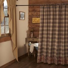 a rustic bathroom with wood walls and flooring is pictured in this image, the shower curtain has plaid fabric on it