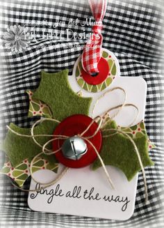 a christmas ornament with holly and bells attached to the tag that says, jingle all the way